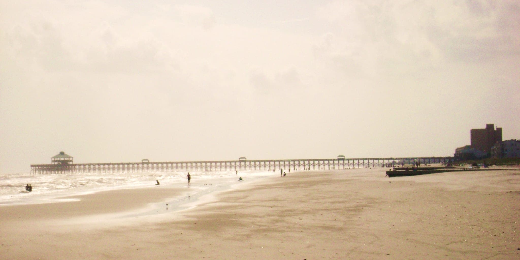 A wide view of the beach at Folly Beach, SC with houses along the dune line