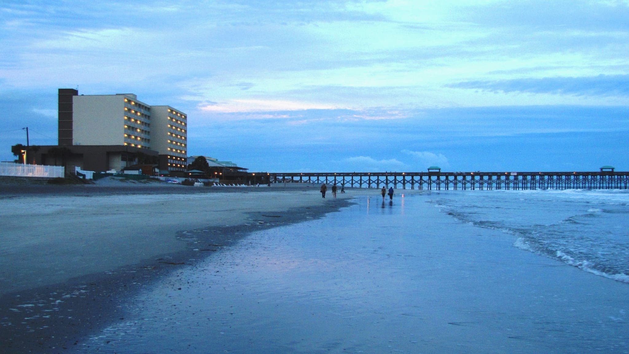 Folly Beach Pier at twilight with wet sand reflecting the lights